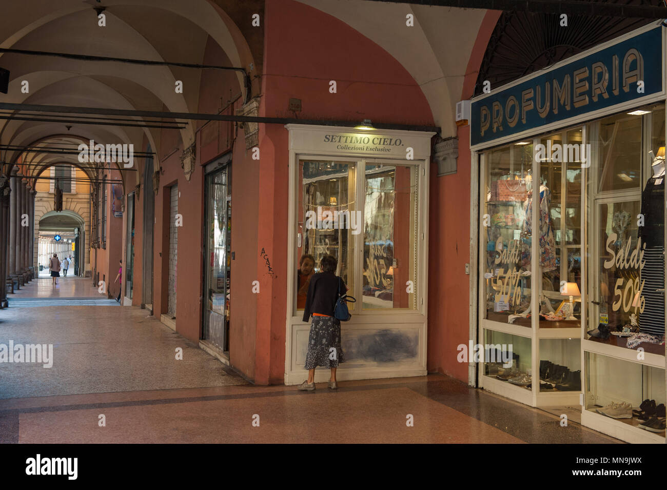 Bologna. Donna anziana guarda nella vetrina di un negozio, portici di Strada Maggiore. L'Italia. Foto Stock