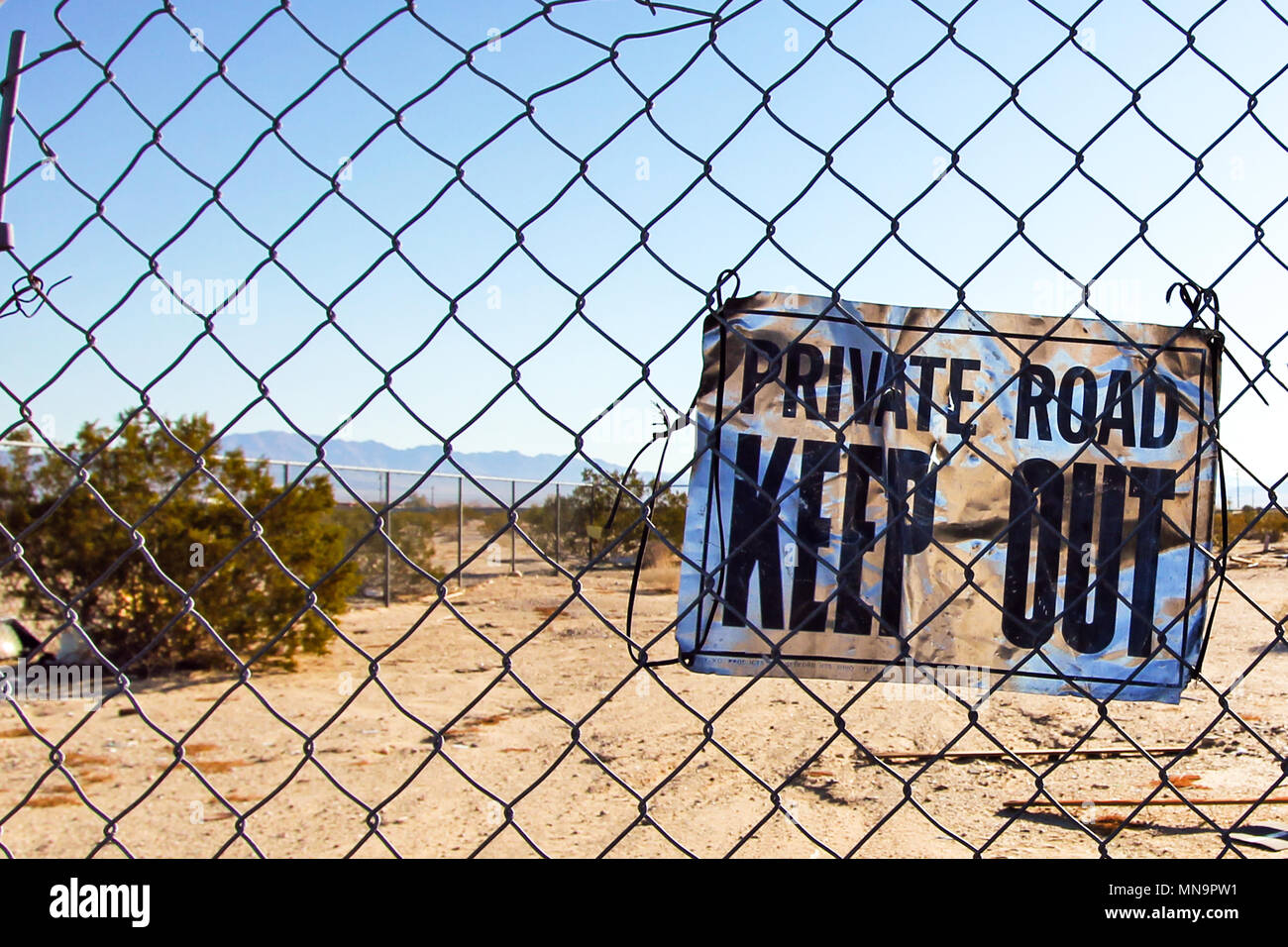 Strada privata Tenere fuori segno sulla catena collegamento recinto protegge un deserto remoto composto nella California High Desert, il Mojave, STATI UNITI D'AMERICA. Foto Stock