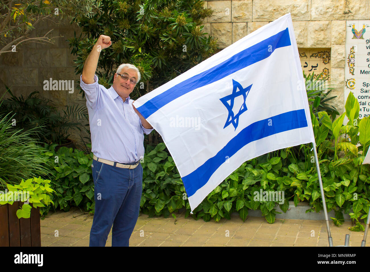 Un vecchio di 70 anni gentile pompe maschio l'aria in solidarietà con Israele mentre si tiene la bandiera nazionale Foto Stock