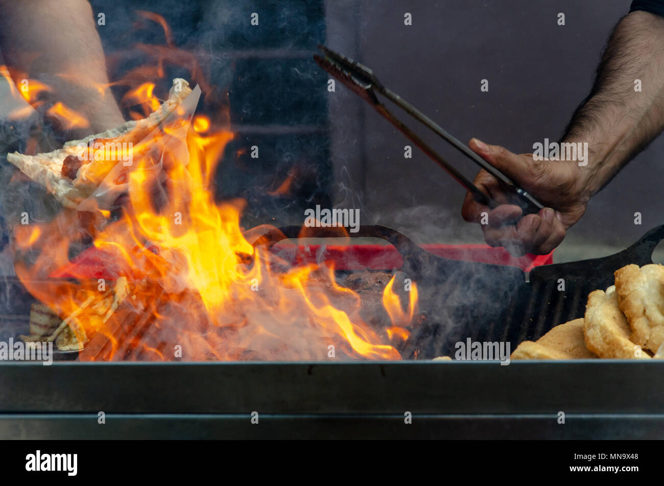 Grill Barbecue il fuoco con le mani e barbecue le tenaglie che serve Foto Stock