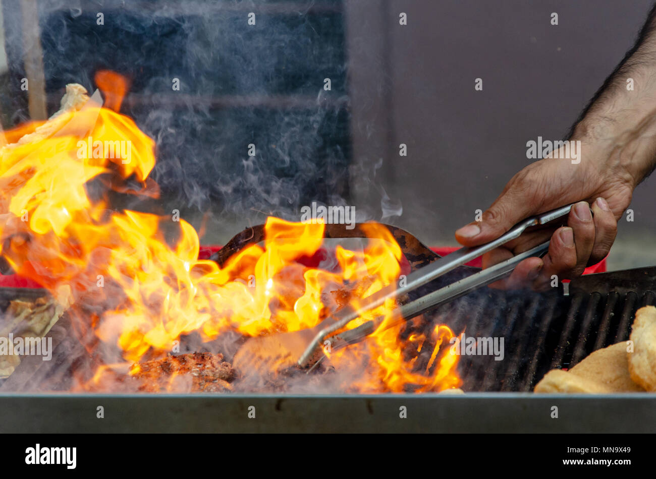 Barbeque il fuoco con le mani e le tenaglie barbecue Foto Stock