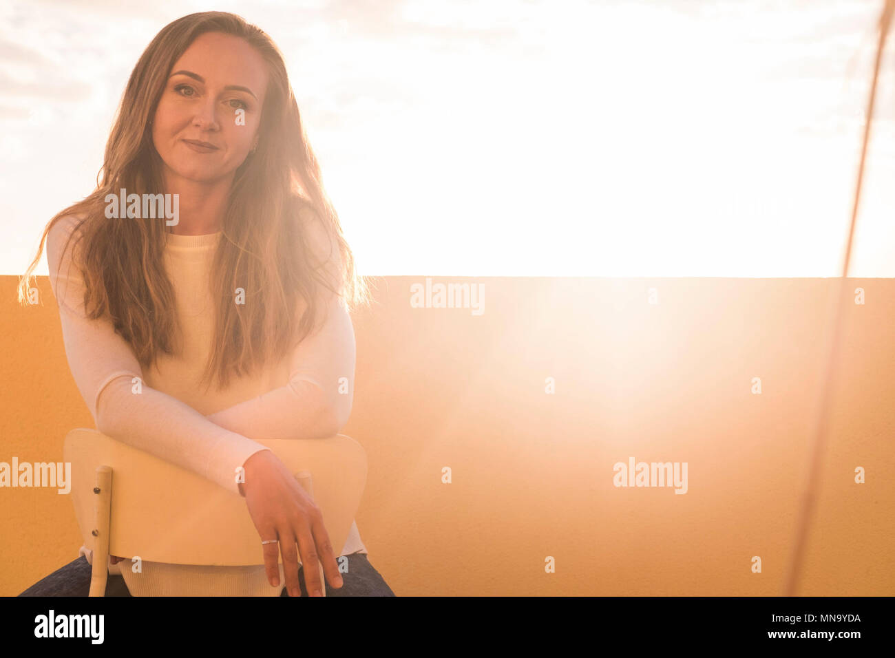 Bellissimo modello caucasian donna bionda sorriso per la fotocamera sotto la luce del sole in controluce. nbright immagine con chiaro cielo bianco e bella gente sul Foto Stock