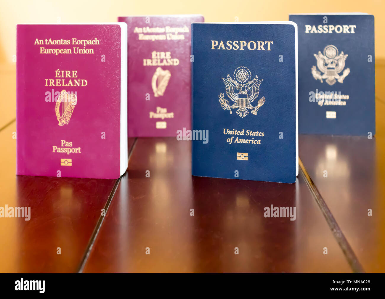 Irlandese (Unione Europea) e gli Stati Uniti d'America i passaporti in piedi accanto a ciascun altro e riflessa su di un tavolo di legno. Foto Stock