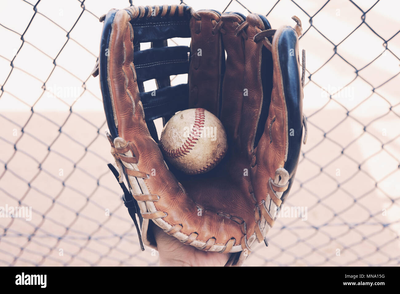 Sport americano di baseball mostra closeup della palla nel guanto di piroga. Campo in background di recinzione, ideale per lo sport grafica. Foto Stock
