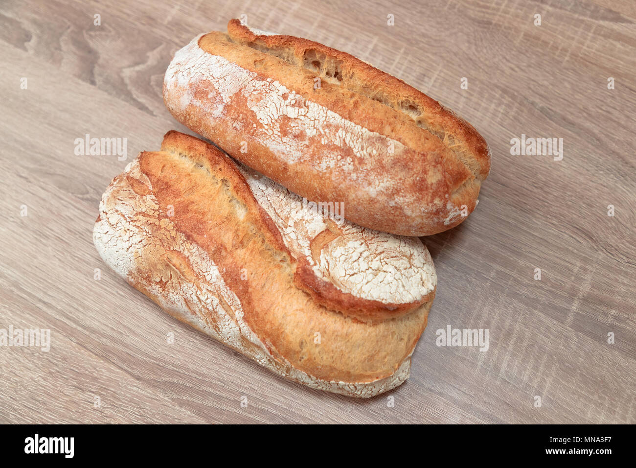 Due gustoso pane cotto su una luce sullo sfondo di legno Foto Stock