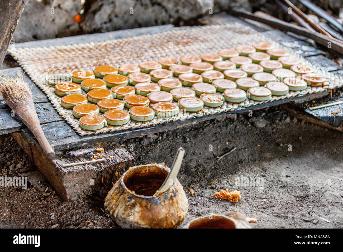 Tradizionale processo di fabbricazione di zucchero di palma nel villaggio a Rote Isola, Indonesia. Spessore 'toddy' (evaporato palm sap) versata in anelli di bambù. Foto Stock