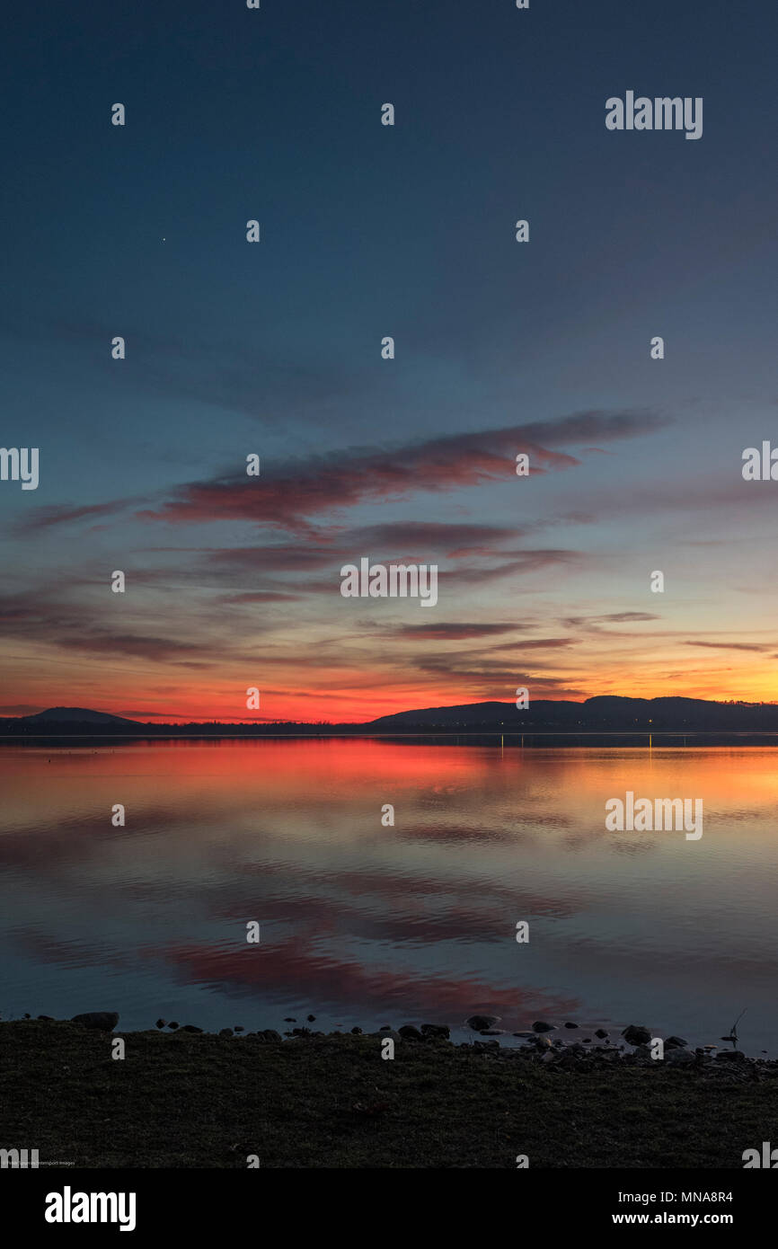 Gropello, provincia di Varese, Lombardia, Italia, vista del tramonto attraverso il Lago di Varese, Lago di Varese, atmosferico, rosso giallo e blu cielo rimbalzare la luce dal sole che tramonta sotto l'orizzonte, © Peter SPURRIER, Foto Stock