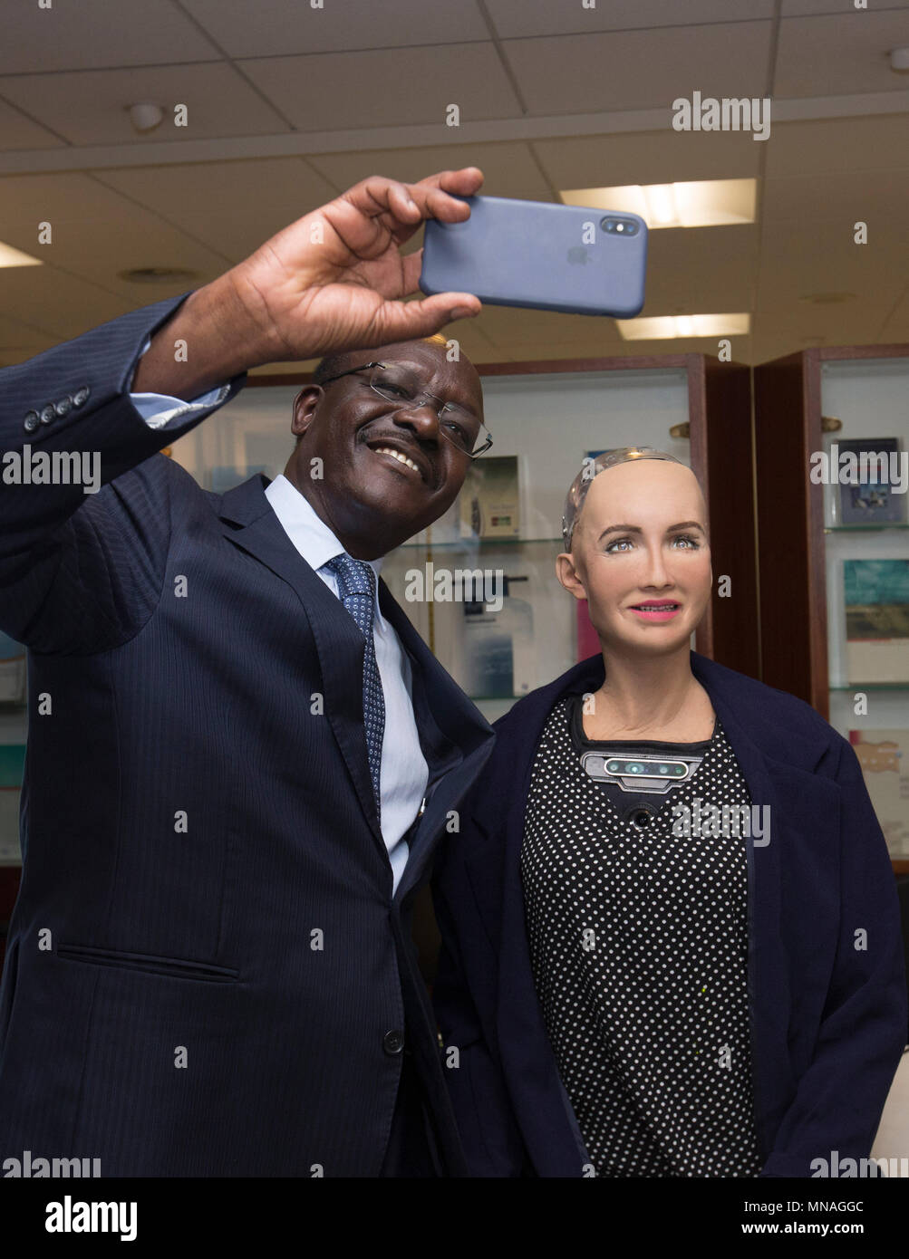 Ginevra, Svizzera. 15 Maggio, 2018. Mukhisa Kituyi (L), Segretario Generale della Conferenza delle Nazioni Unite sul commercio e lo sviluppo (UNCTAD), pone per un selfie con Robot Sophia, una intelligenza artificiale robot umanoide, alla seconda AI per un buon Vertice mondiale a Ginevra, in Svizzera, il 15 maggio 2018. La seconda AI per un buon Vertice Mondiale ha dato dei calci a fuori a Ginevra il martedì. Credito: Xu Jinquan/Xinhua/Alamy Live News Foto Stock