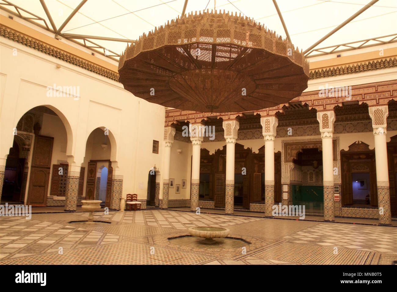 Il Museo di Marrakech è alloggiato nel modulo DAR Menebhi Palace. L'atrio ha un lampadario a bracci costituiti da piastre di metallo decorato con tagli geometrici Foto Stock