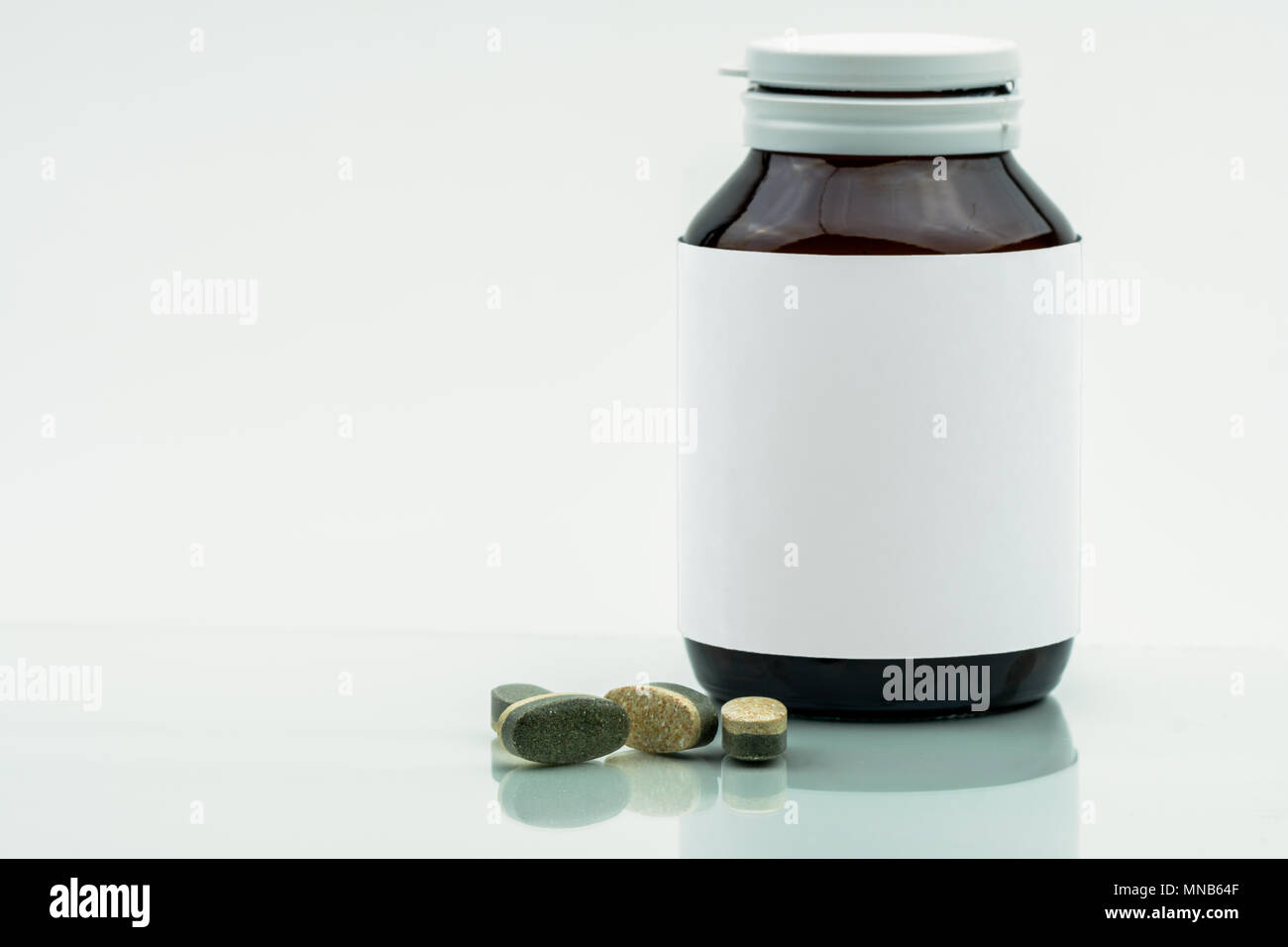 Vitamine, supplementi minerali e dual layer compresse pillole e medicina flacone di vetro ambrato con etichetta vuota isolata su sfondo bianco con copia sp Foto Stock