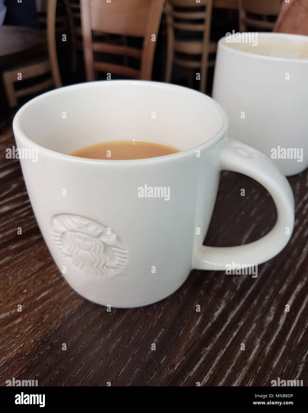 Tazza di tè con Starbucks logo su un tavolo con sedie in background Foto Stock