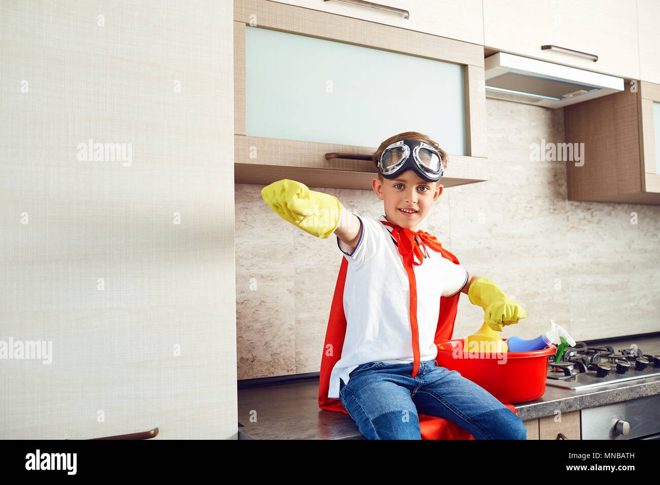 Un ragazzo vestito come un supereroe in cucina Foto Stock
