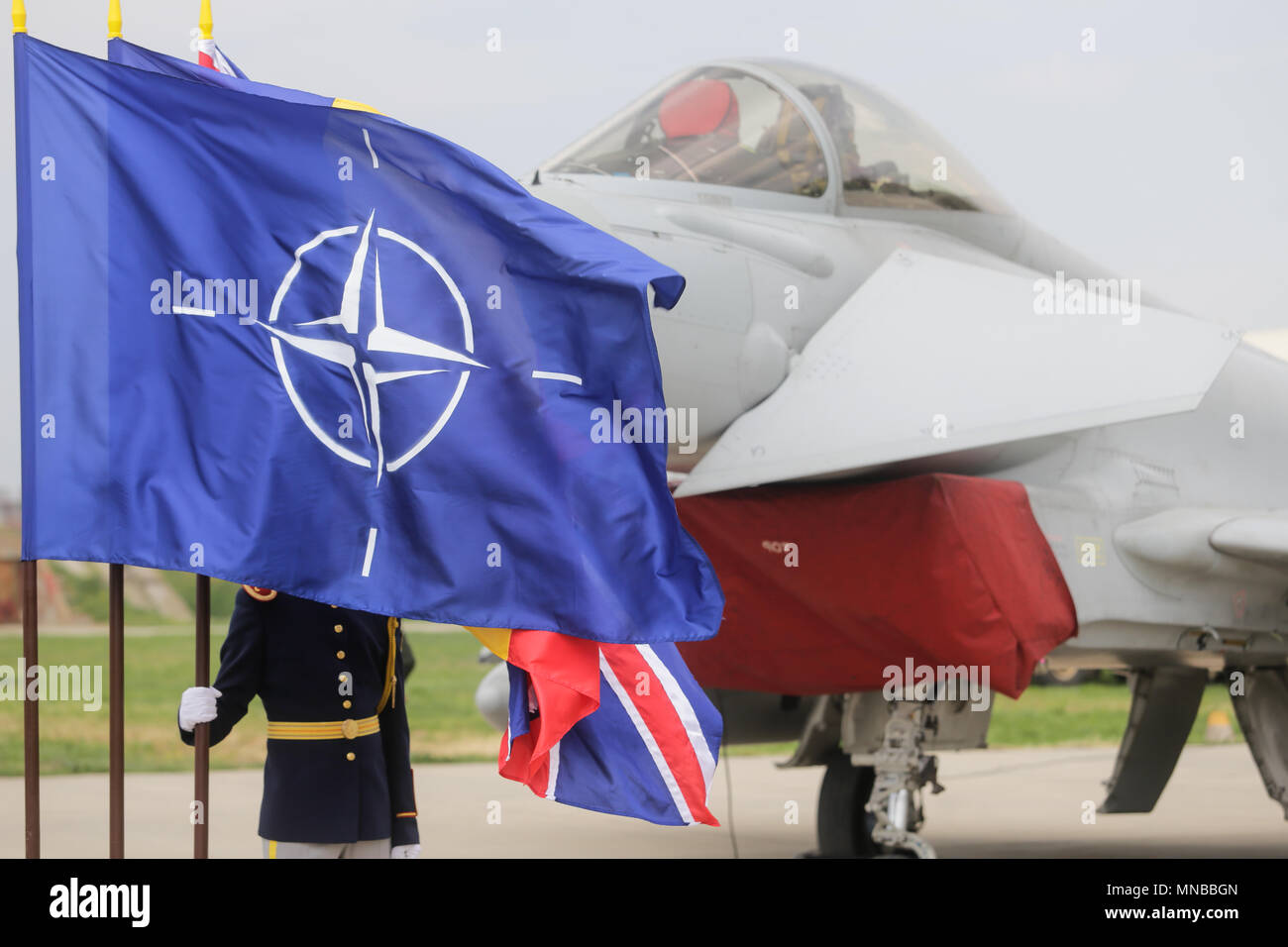 MIHAIL KOGALNICENU, Romania - 27 aprile una guardia rumeno può essere visto dietro la NATO, Regno Unito e Romania flag, mentre un Royal Air Force Eurofighter Typhoon Foto Stock
