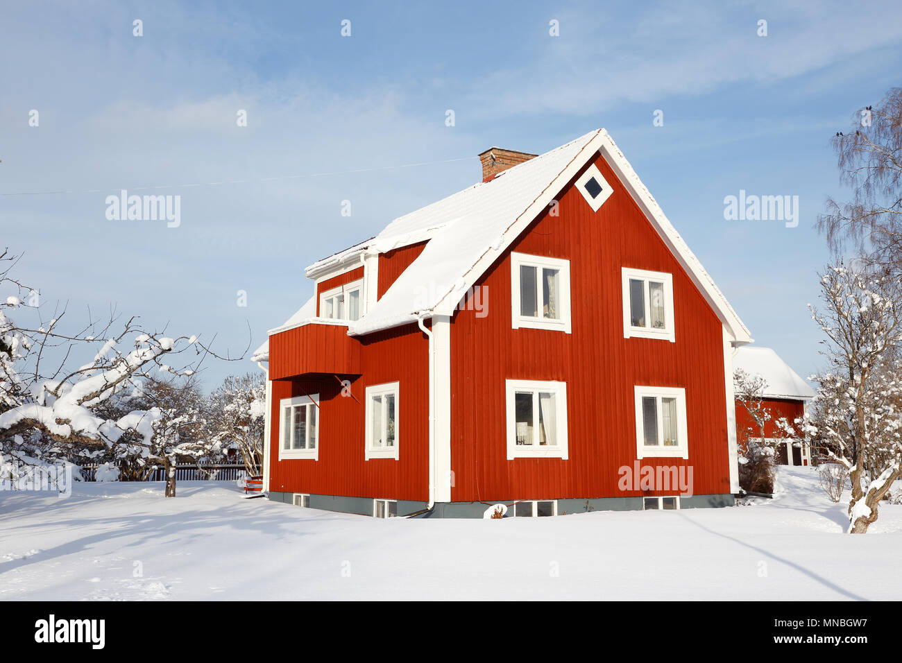 Due storie svedese rosso più vecchi casa familiare con basment con una coperta di neve giardino durante la stagione invernale. Foto Stock