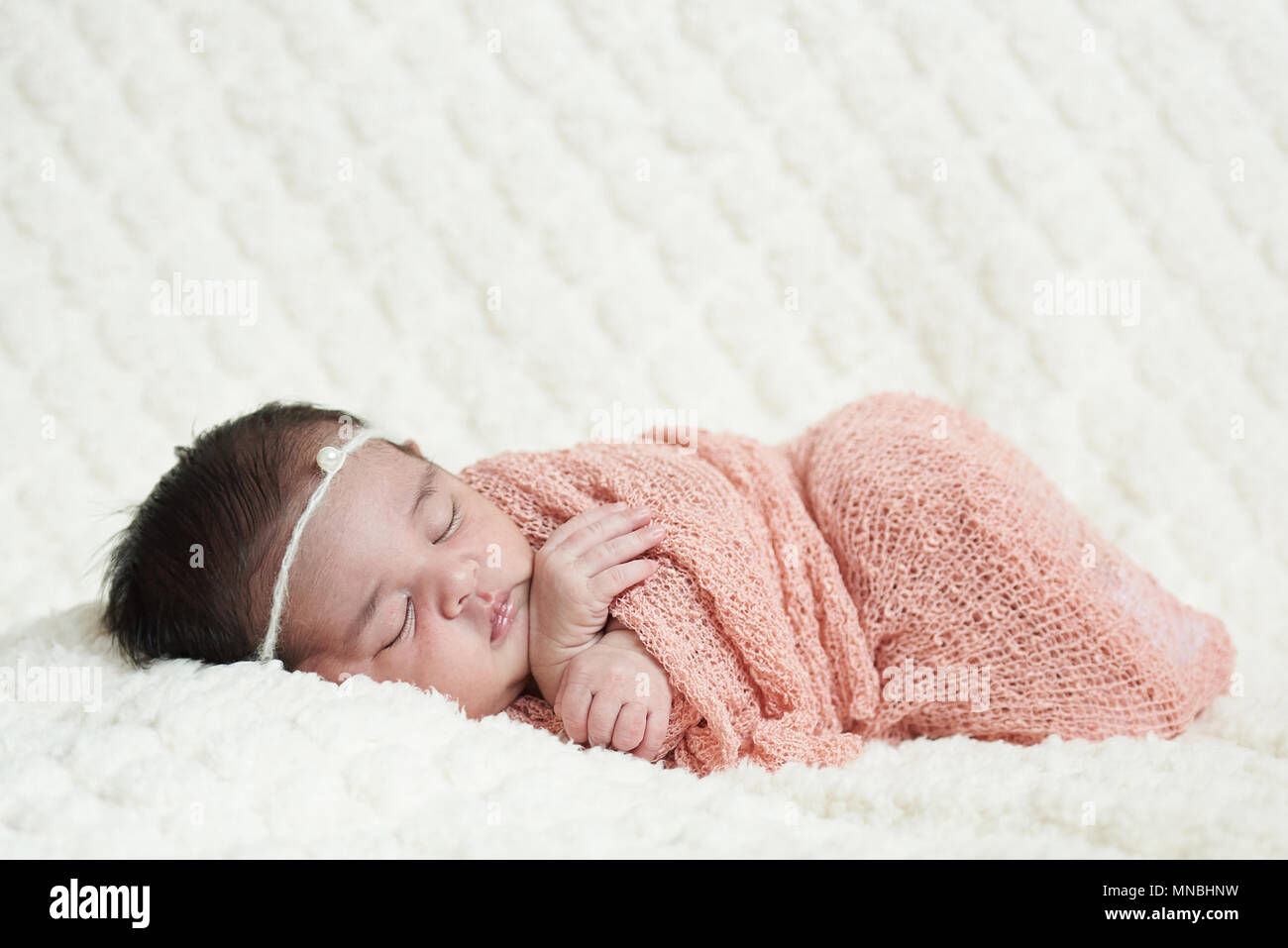 Carino neonato dormire sulla soffice coltre bianca sullo sfondo Foto Stock