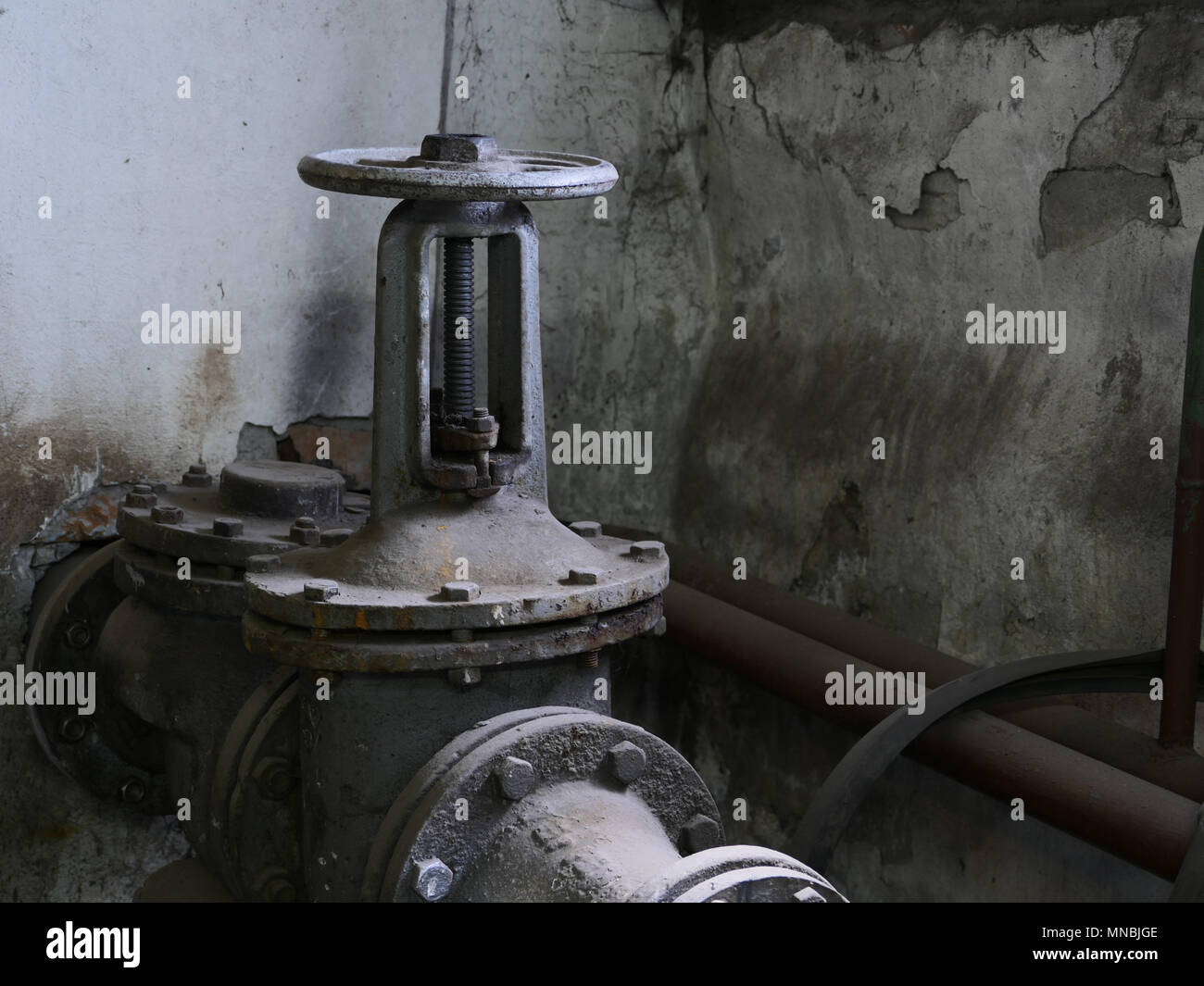 Vecchio ghisa valvola sulla pipeline nel seminterrato Foto Stock