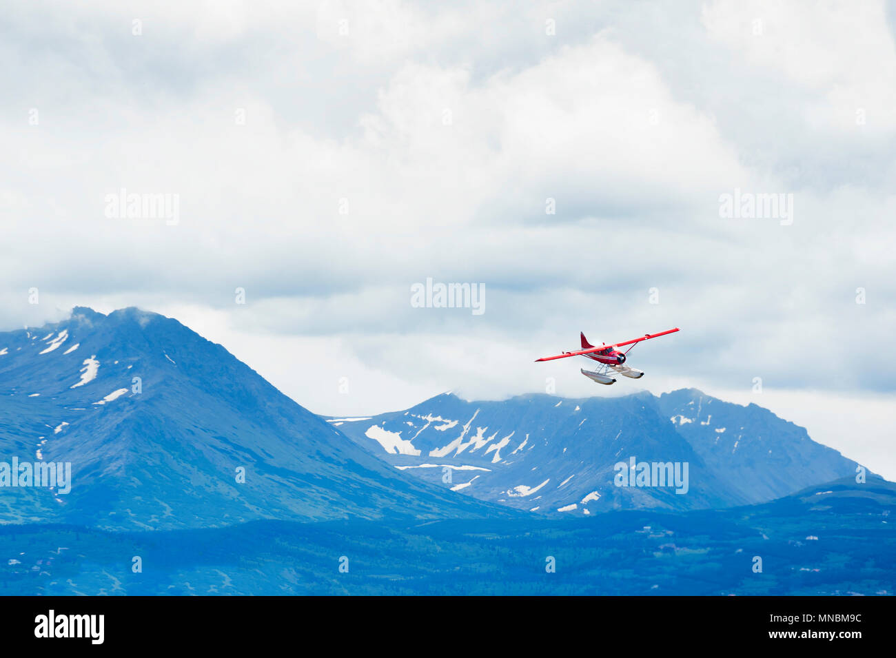 CHugach Mountain Range sotto cieli nuvolosi fornisce un maestoso torna a goccia a bordo di un idrovolante che si prepara a terra presso il lago di cofano in Anchorage in Alaska,. Foto Stock