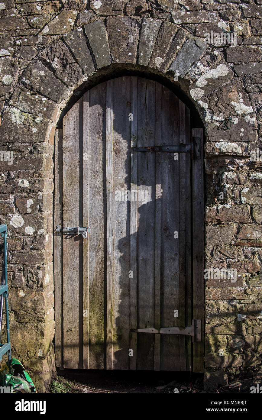 Una vecchia porta di legno insieme in un vecchio muro di pietra Foto Stock