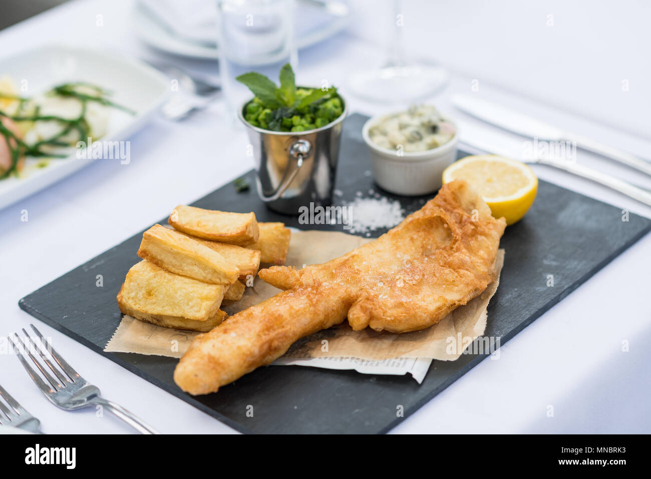 Pesce e patatine con piselli e salsa tartare Foto Stock