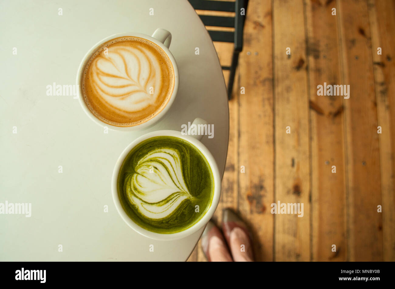 Due tazze di tè matcha e cappuccino con belle latte art sul colore grigio nella tabella. Foto Stock