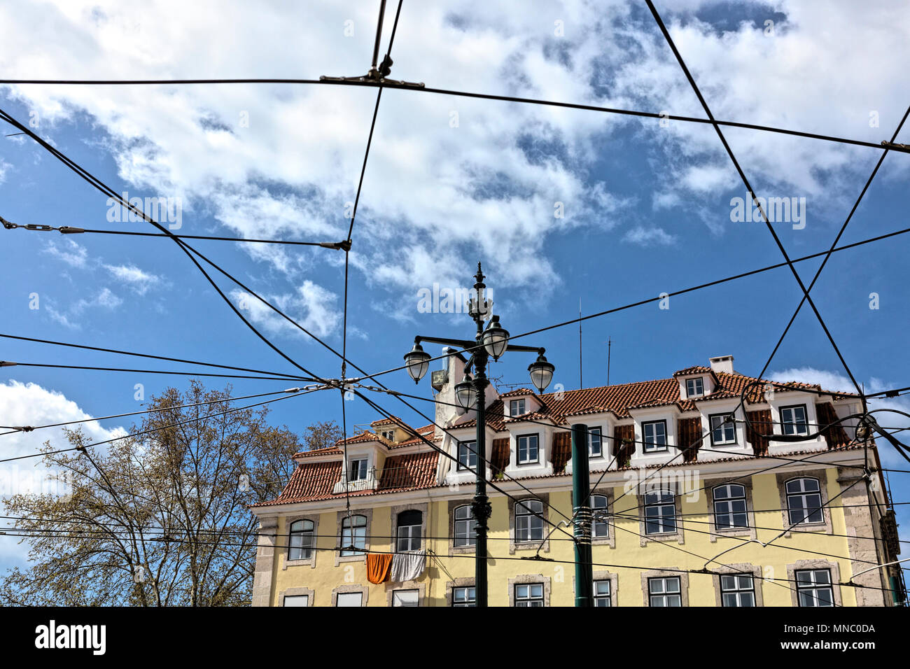 Basso angolo vista townhouses attraverso il tettuccio di fili del tram a Lisbona Foto Stock