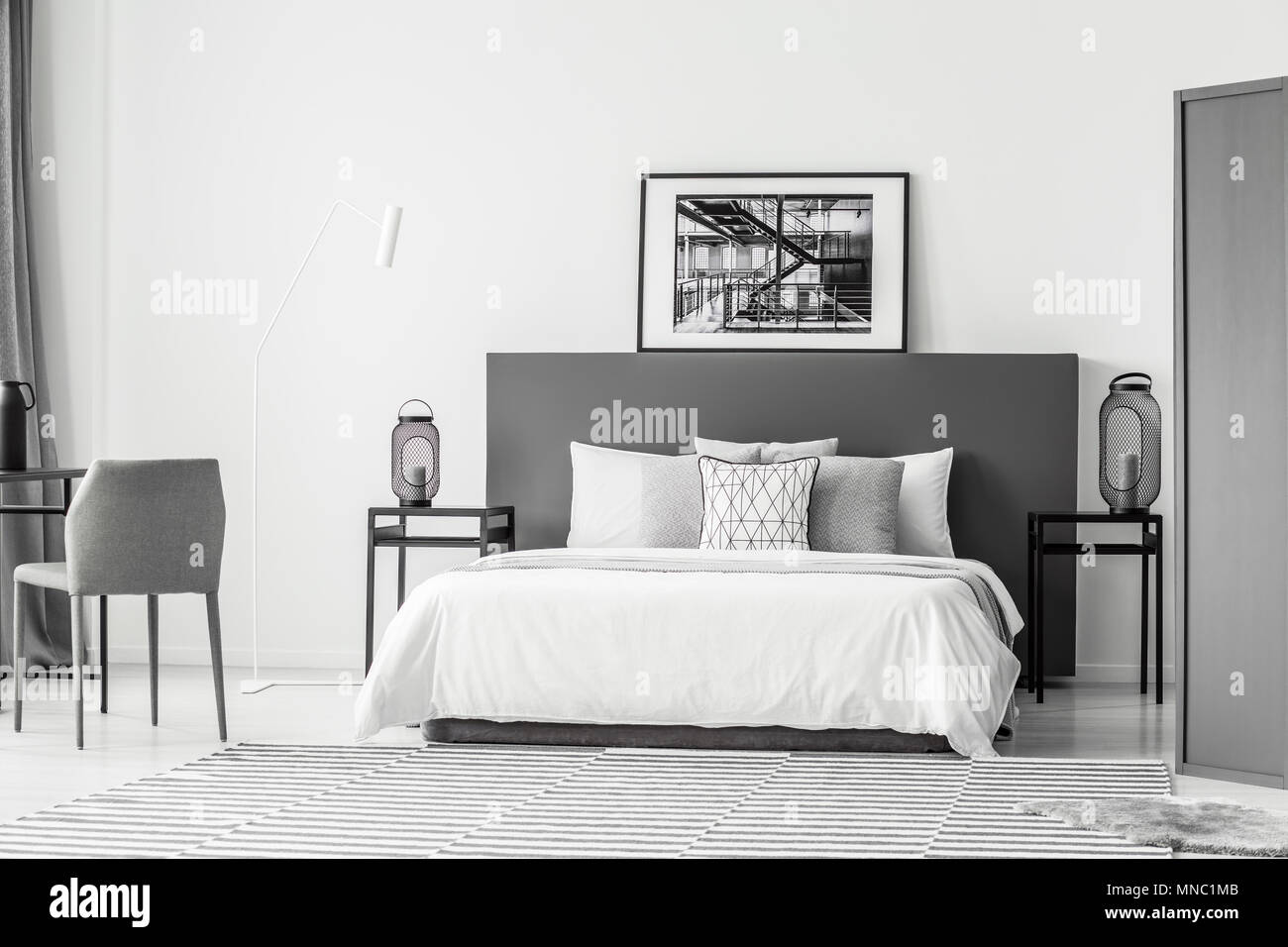 Letto bianco tra le tabelle con lanterne in hotel bedroom interno con poster su grigio testata Foto Stock