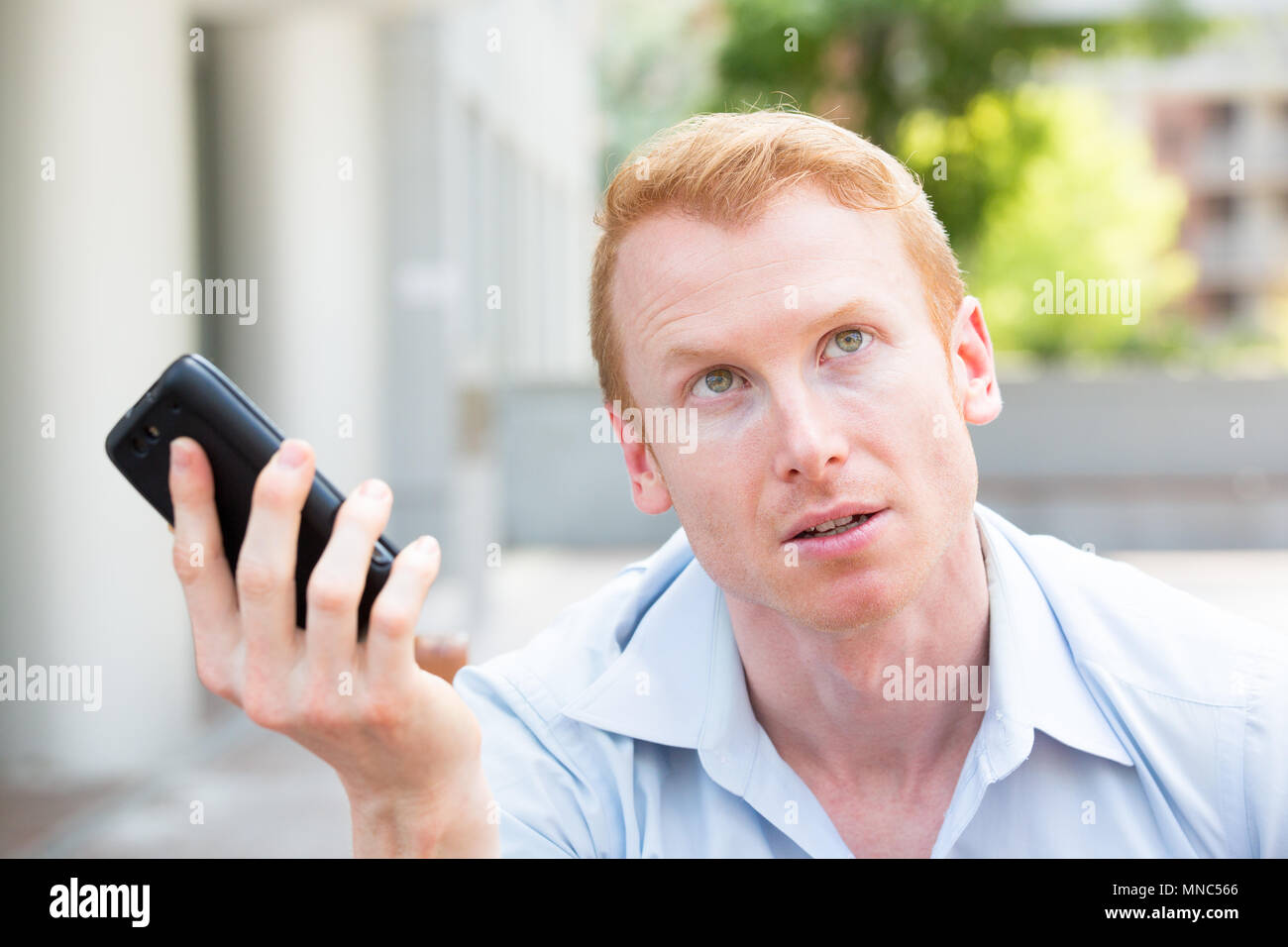 Closeup Ritratto, giovane arrabbiato, frustrato incazzato da qualcuno a parlare sul suo telefono cellulare, cattive notizie, isolata all'esterno al di fuori dello sfondo. Lo Foto Stock