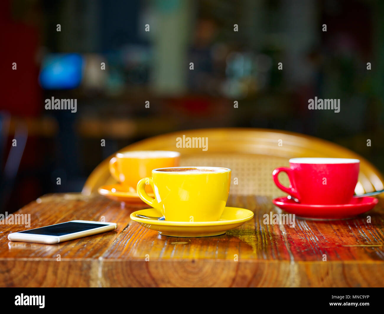 Tre tazze di cappuccino e un cellulare sul tavolo in un caffè Foto Stock