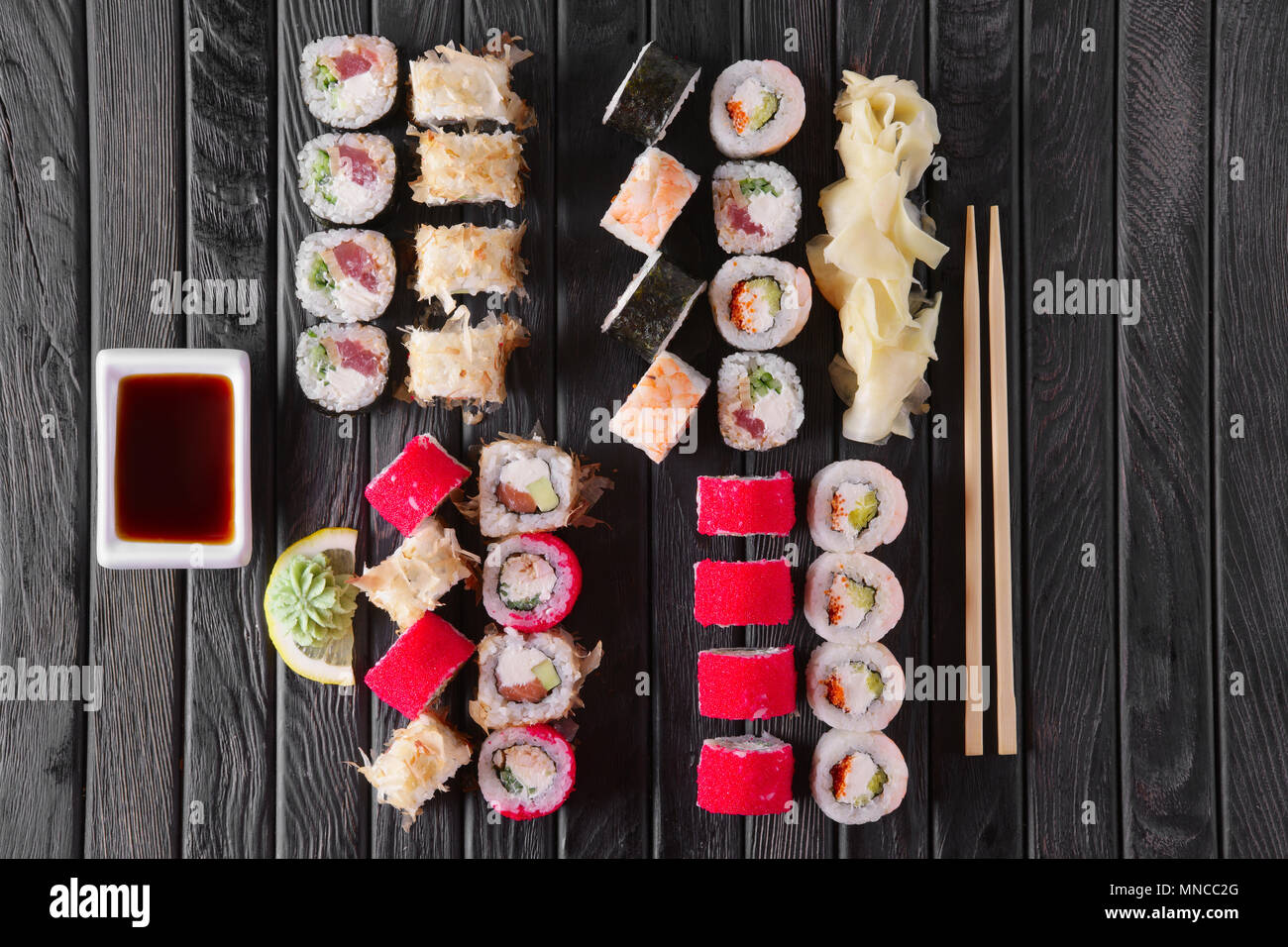 Ampia serie di rotoli con guarnire e hashi sul piatto di legno Foto Stock