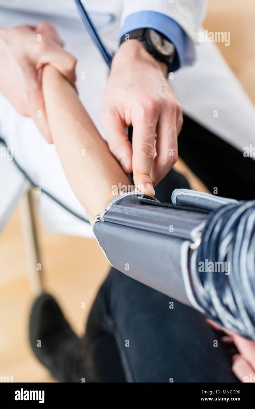 La mano di un medico la misurazione della pressione del sangue di un paziente Foto Stock