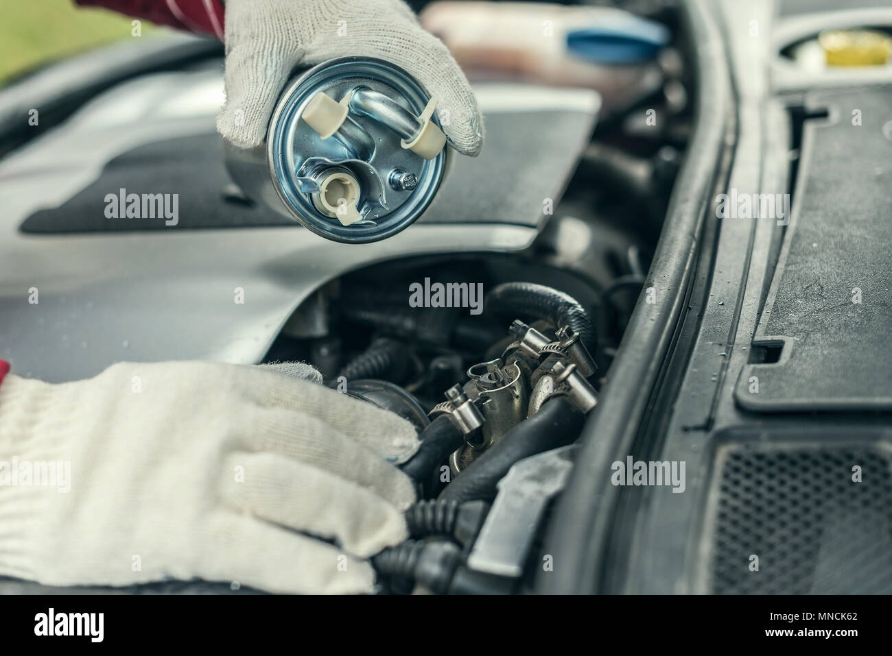 Un meccanico automatico sostituisce un auto del filtro del carburante. Foto Stock