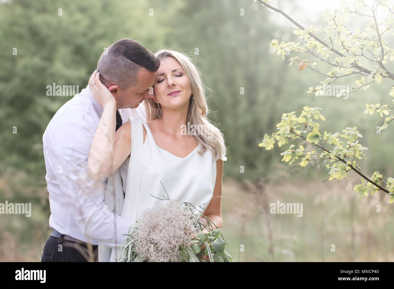 Bella gente amore kissing, sposi novelli, una coppia giovane, sessione outdoor. La sposa in un abito bianco. Amore, matrimonio e passione Foto Stock