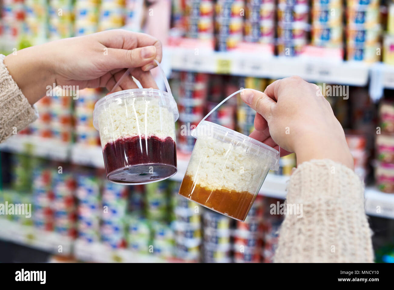 Acquirente mani con contenitore di plastica di ricotta con marmellata nel negozio di alimentari Foto Stock