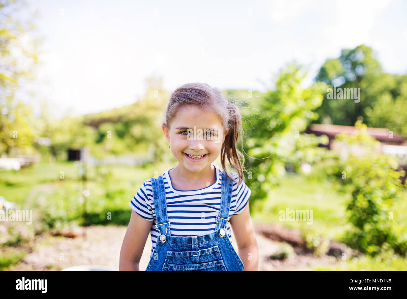 Un ritratto di una piccola ragazza in giardino in primavera la natura. Foto Stock
