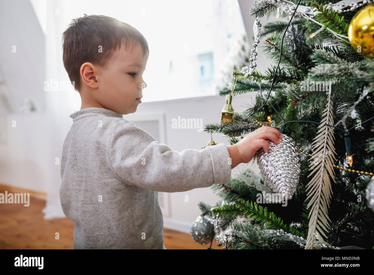 Vista laterale del ragazzo accanto a albero di Natale a casa Foto Stock