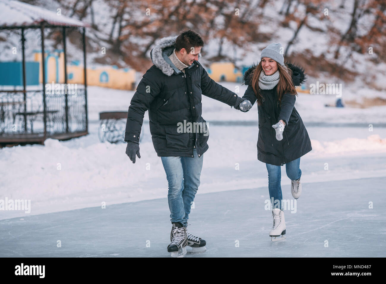 Per tutta la lunghezza della coppia felice tenendo le mani mentre godendo del pattinaggio su ghiaccio Foto Stock