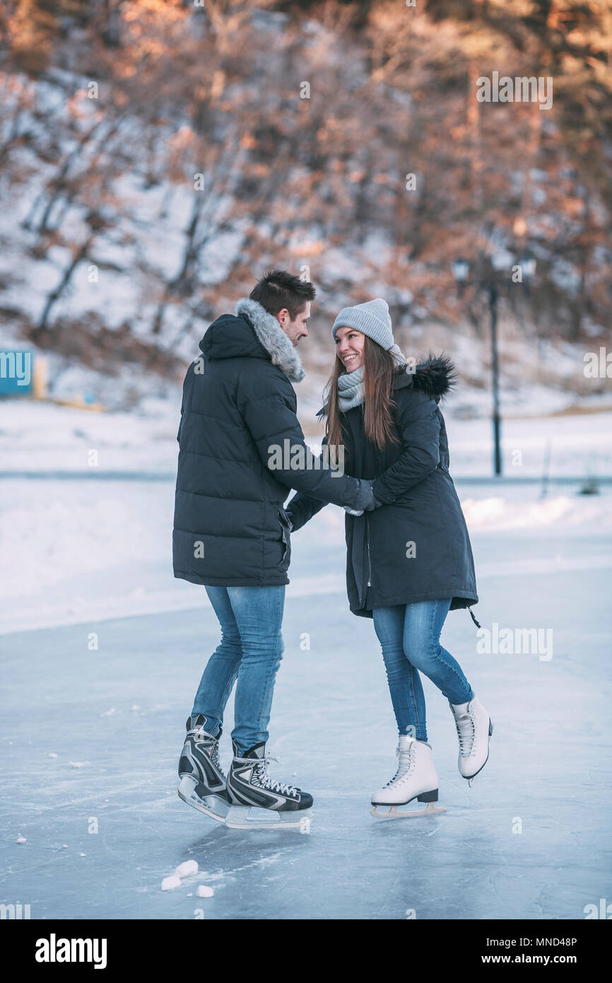 Per tutta la lunghezza della coppia felice tenendo le mani sulla pista di pattinaggio su ghiaccio Foto Stock