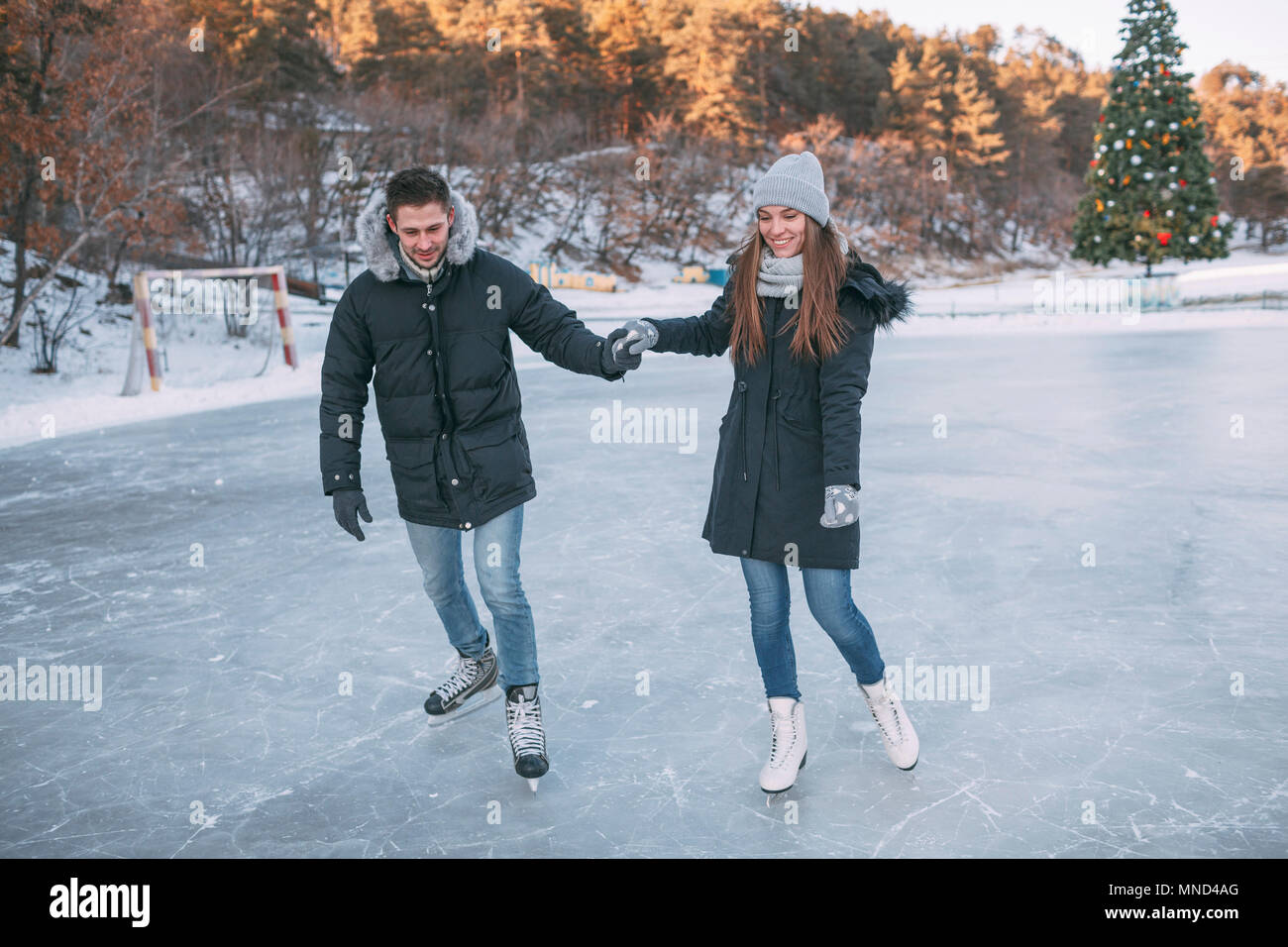 Per tutta la lunghezza della coppia felice godendo di pattinaggio su ghiaccio tenendo le mani Foto Stock