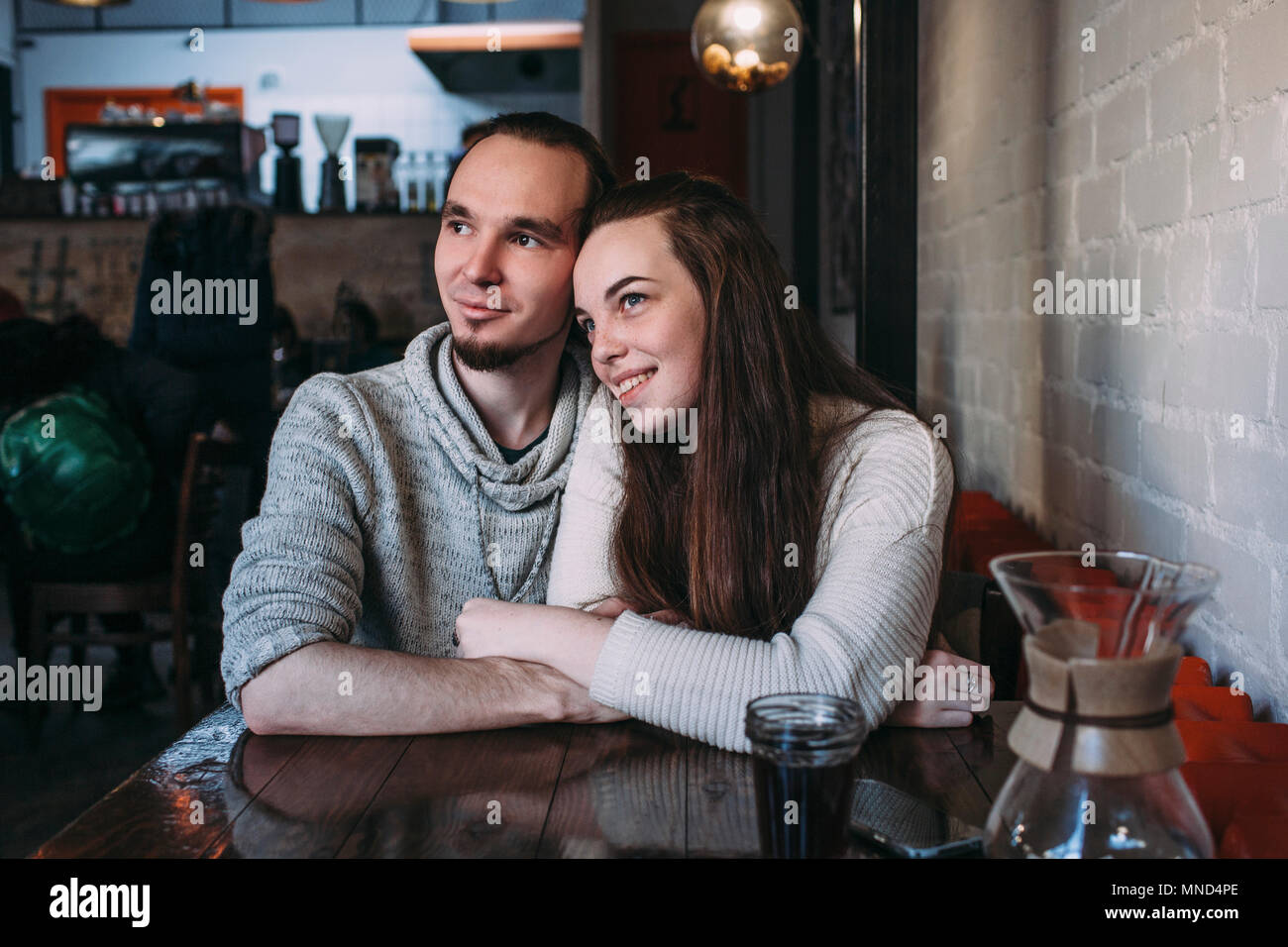 Felice coppia giovane che guarda lontano mentre è seduto presso il cafe Foto Stock
