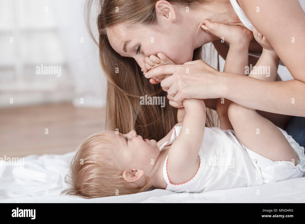 Giocoso madre e figlia sul letto di casa Foto Stock