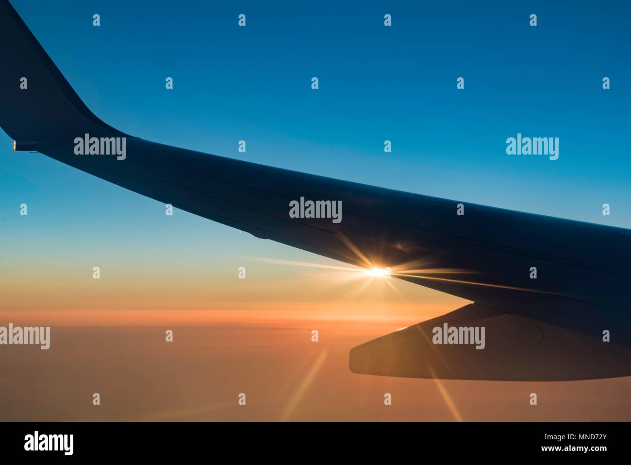 Una silhouette dell'ala di un Boeing 737 jetliner che vola in quota con il sole che tramonta dal bordo dell'ala Foto Stock