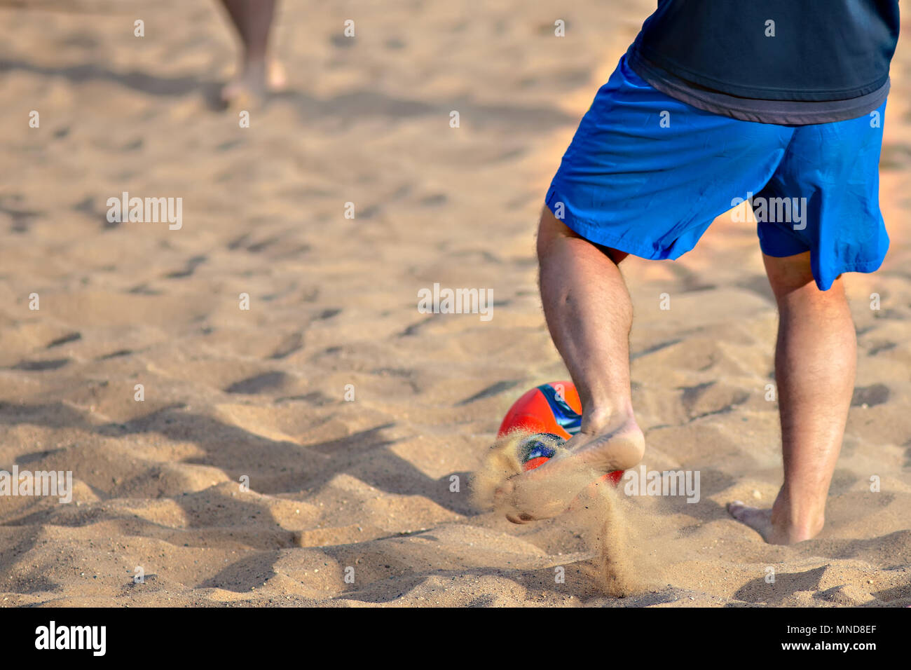 Gli uomini giocano a calcio sulla spiaggia. Sfera rossa Foto Stock