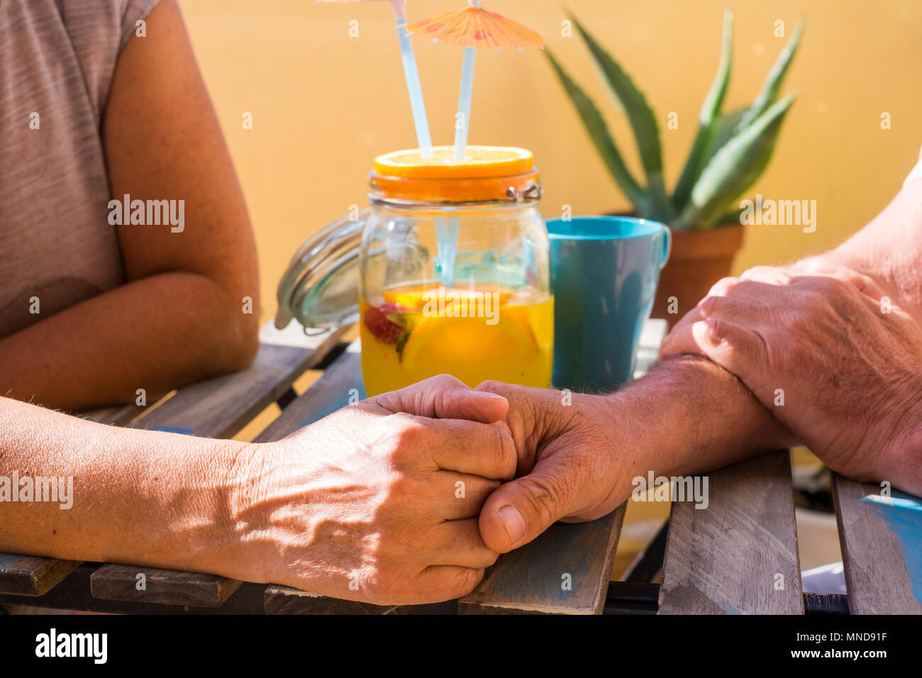 Mano a mano per una coppia senior su una tabella con un cocktail di frutta. Amore per sempre insieme. Foto Stock