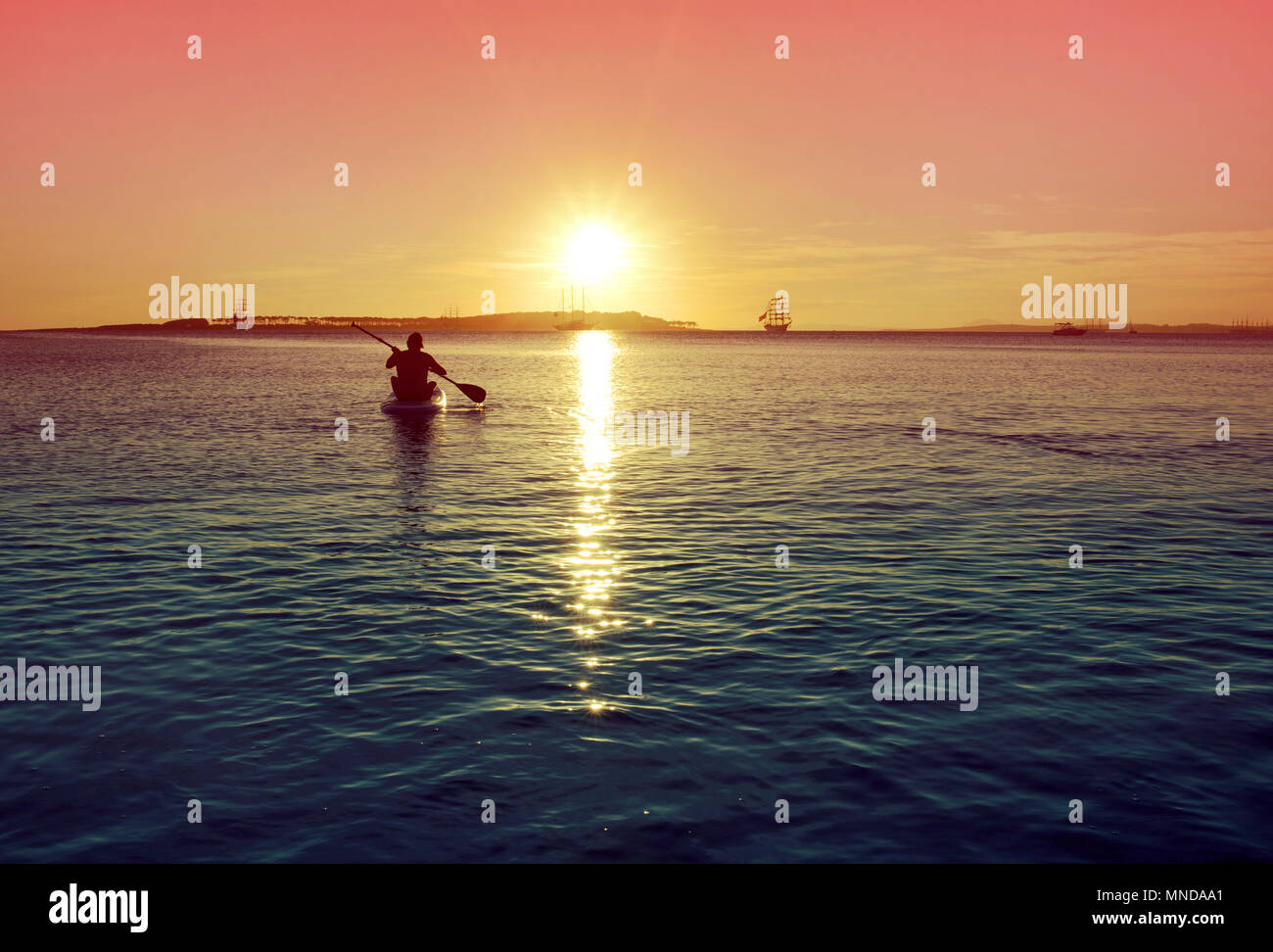 L'uomo paddleboarding durante il tramonto sulla spiaggia di Punta del Este, Uruguay. Foto Stock
