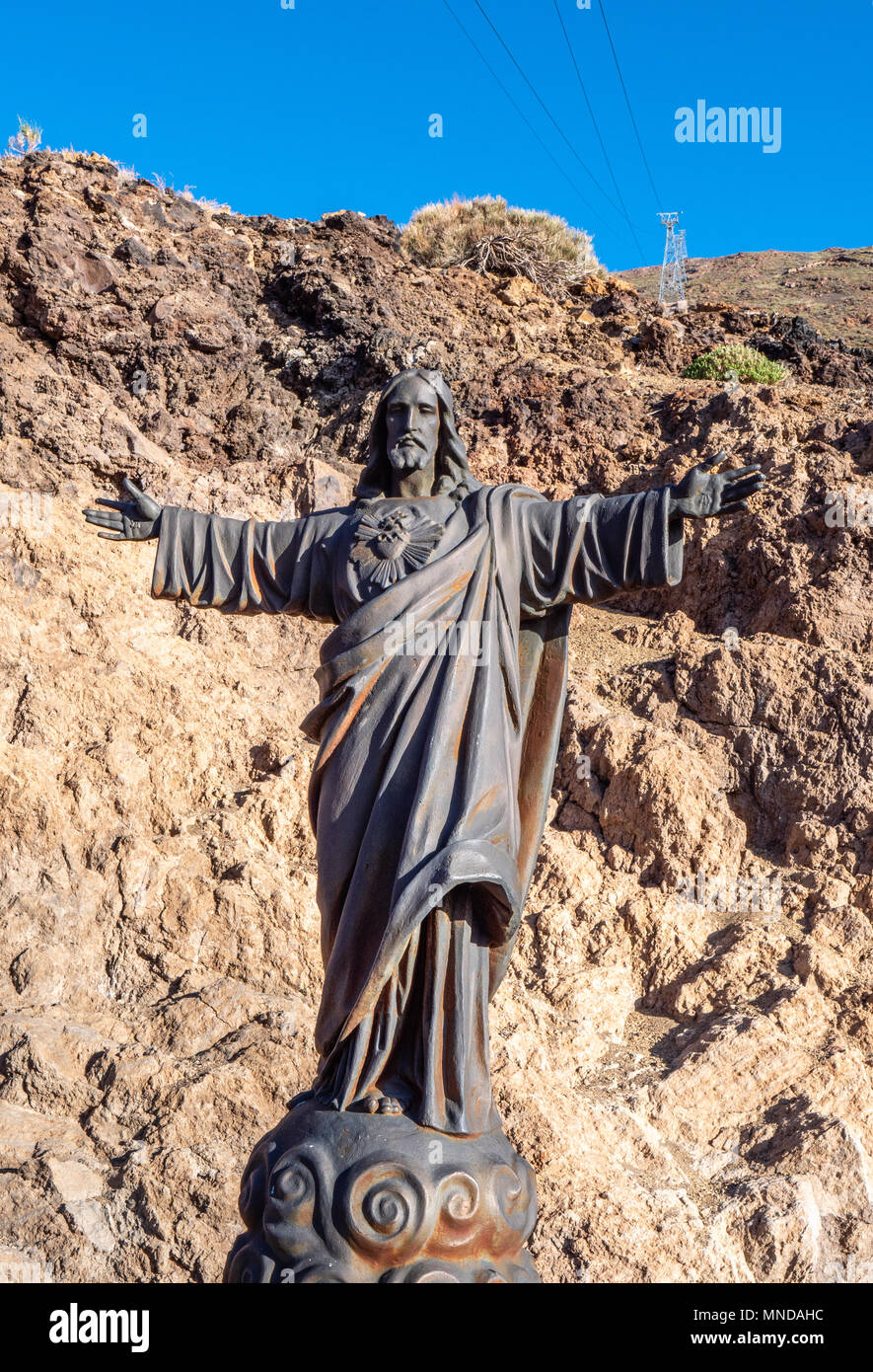 La scultura in bronzo di Gesù Cristo abbracciando pongono in cima ad un vulcano che erutta dalla funivia per la cima di El vulcano Teide Tenerife Isole Canarie Foto Stock