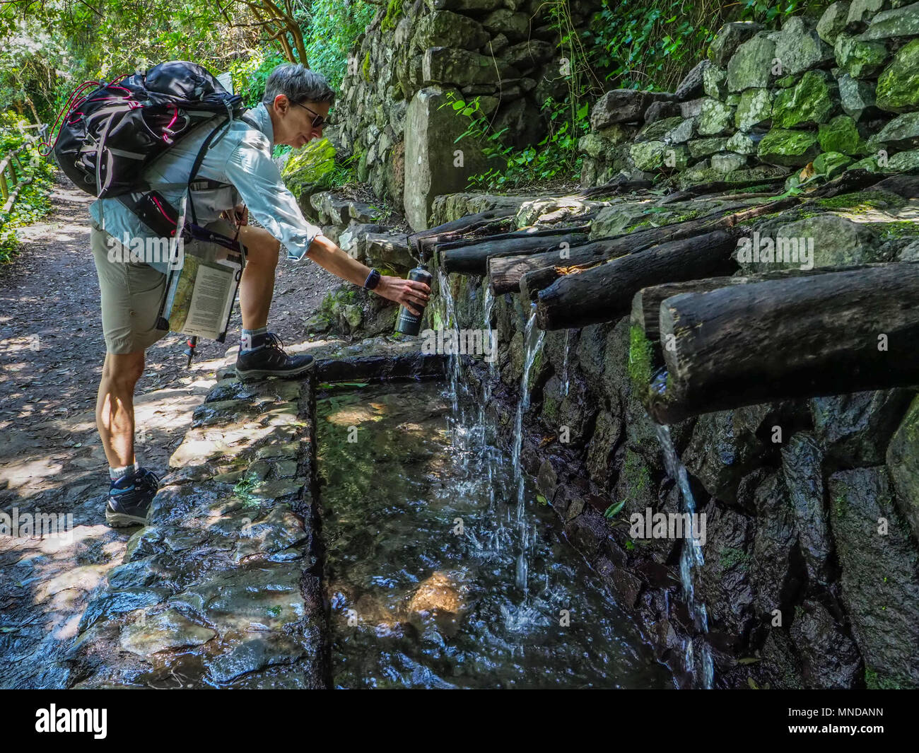 Walker prendere l'acqua dalla sorgente di Chorros de Efina a la Gomera nelle Isole Canarie Spagna ha detto di avere proprietà curative e portare buona fortuna Foto Stock