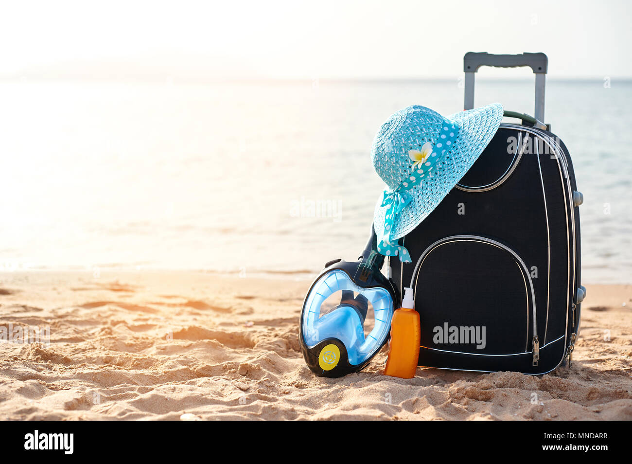 Valigia e cappello, crema solare con una maschera. Il mare tropicale, spiaggia in background. Il concetto di ricreazione di estate viaggi e traffico crocieristico Foto Stock
