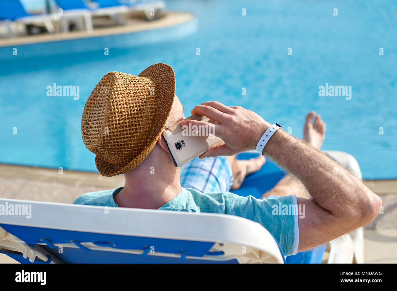 Uomo che utilizza il telefono cellulare in vacanza presso la piscina in hotel, il concetto di un libero professionista che lavora per se stesso su viaggi e vacanze Foto Stock