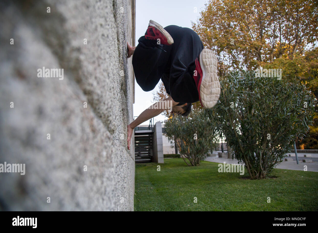 Giovane uomo facendo un incredibile parkour trucco facendo un giro su una parete in strada. Foto Stock