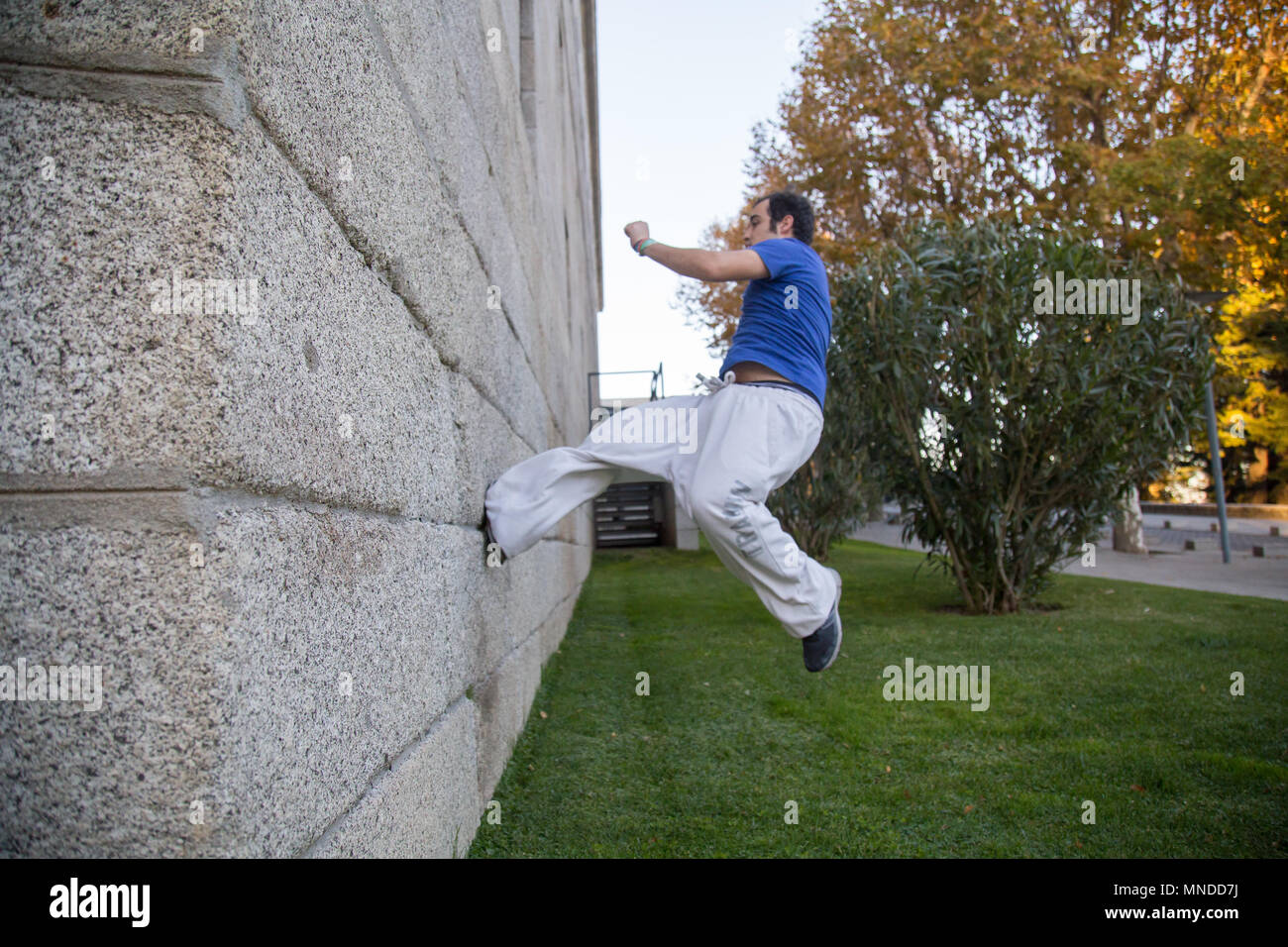 Giovane uomo facendo un incredibile parkour trucco facendo un giro su una parete in strada. Foto Stock